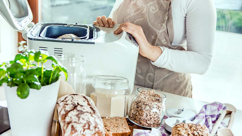 woman using bread maker at home